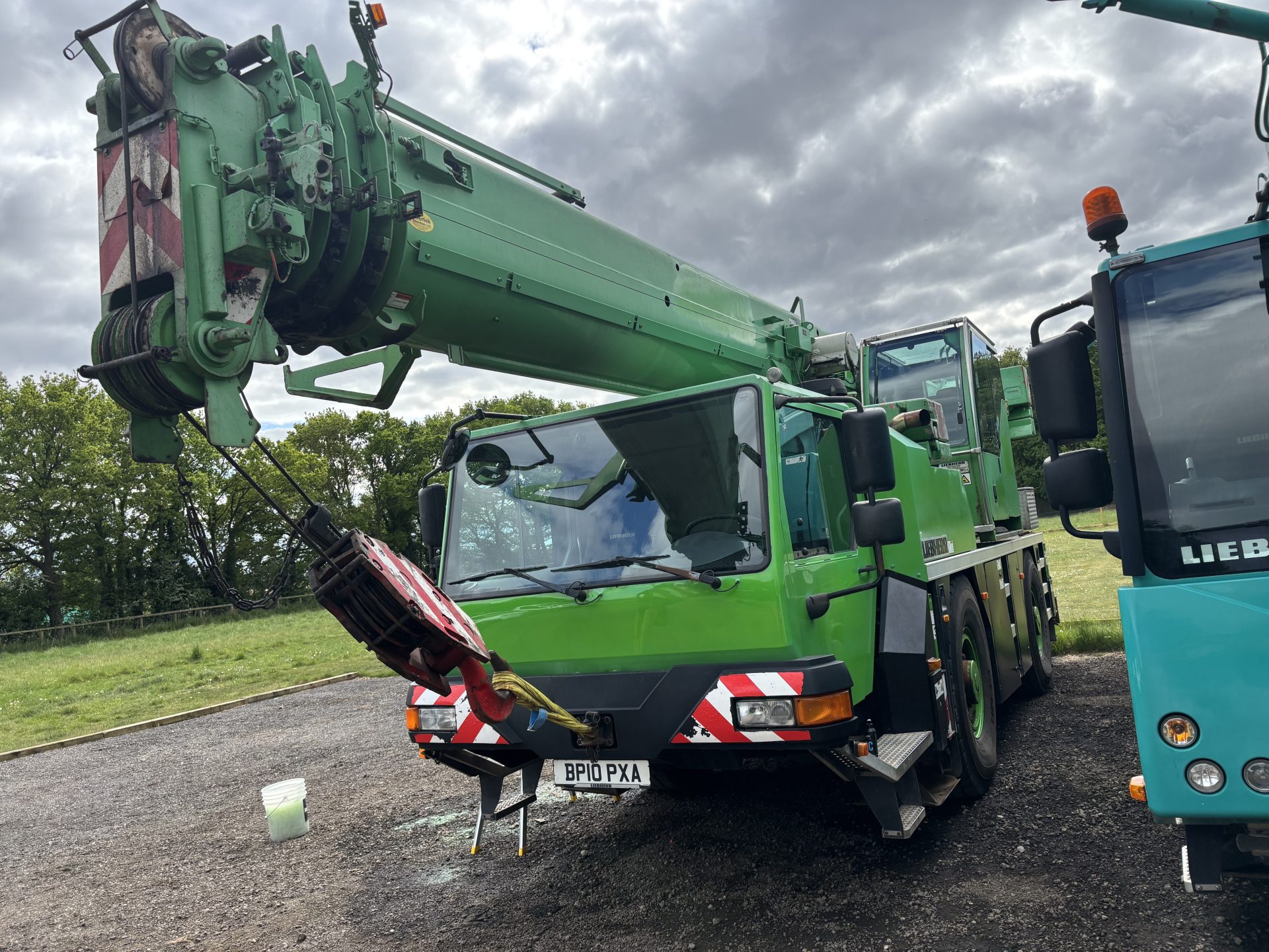 Green crane with stabilisers deployed on roadside