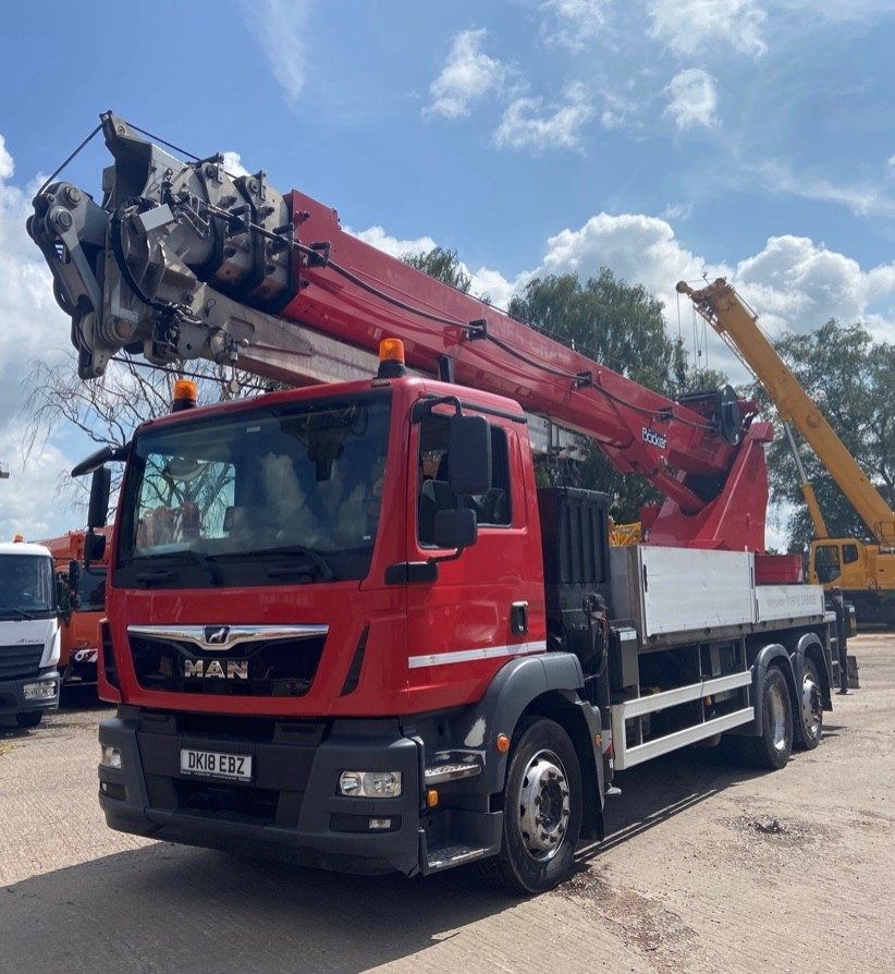 Red crane with extended boom on construction site