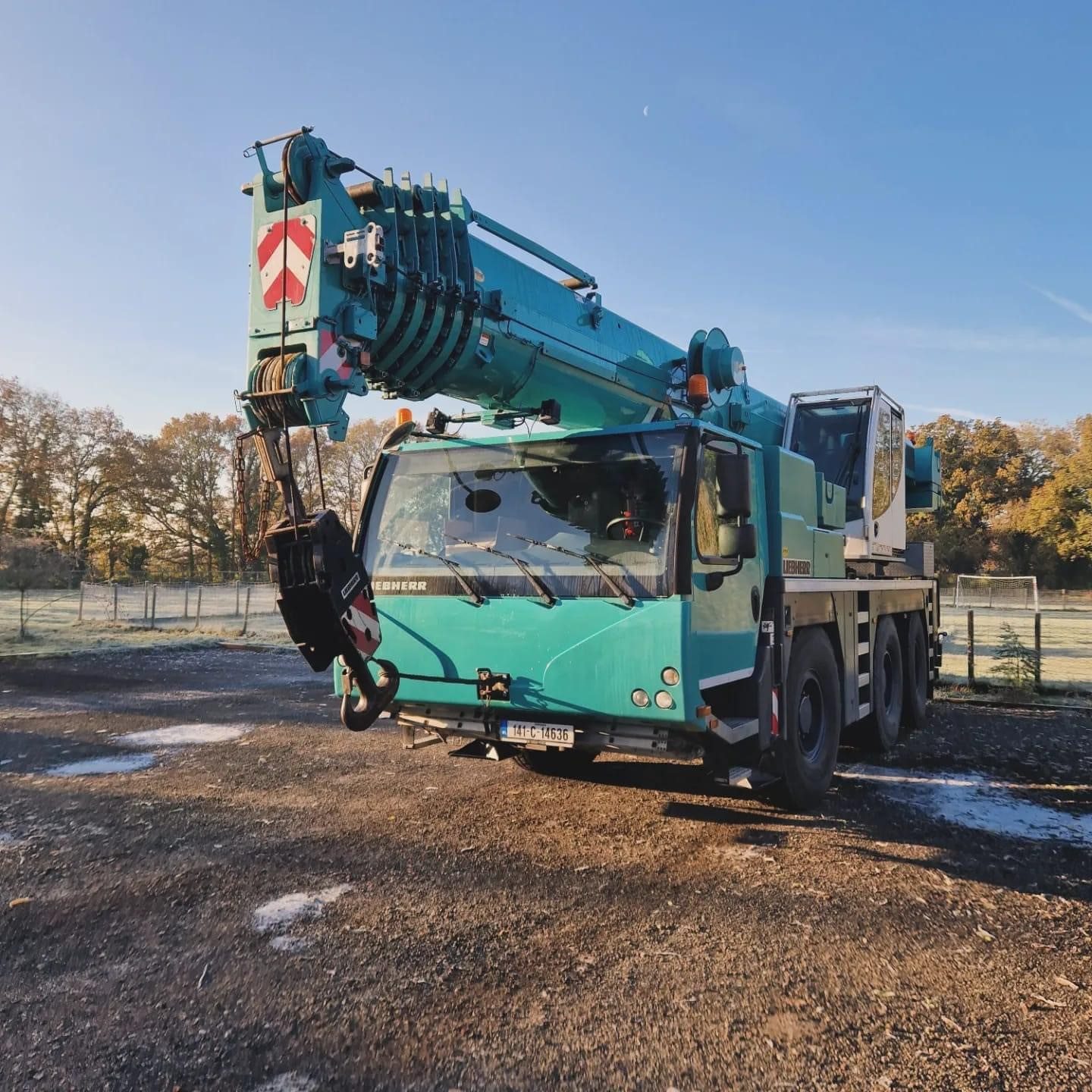 Turquoise crane lifting large industrial unit