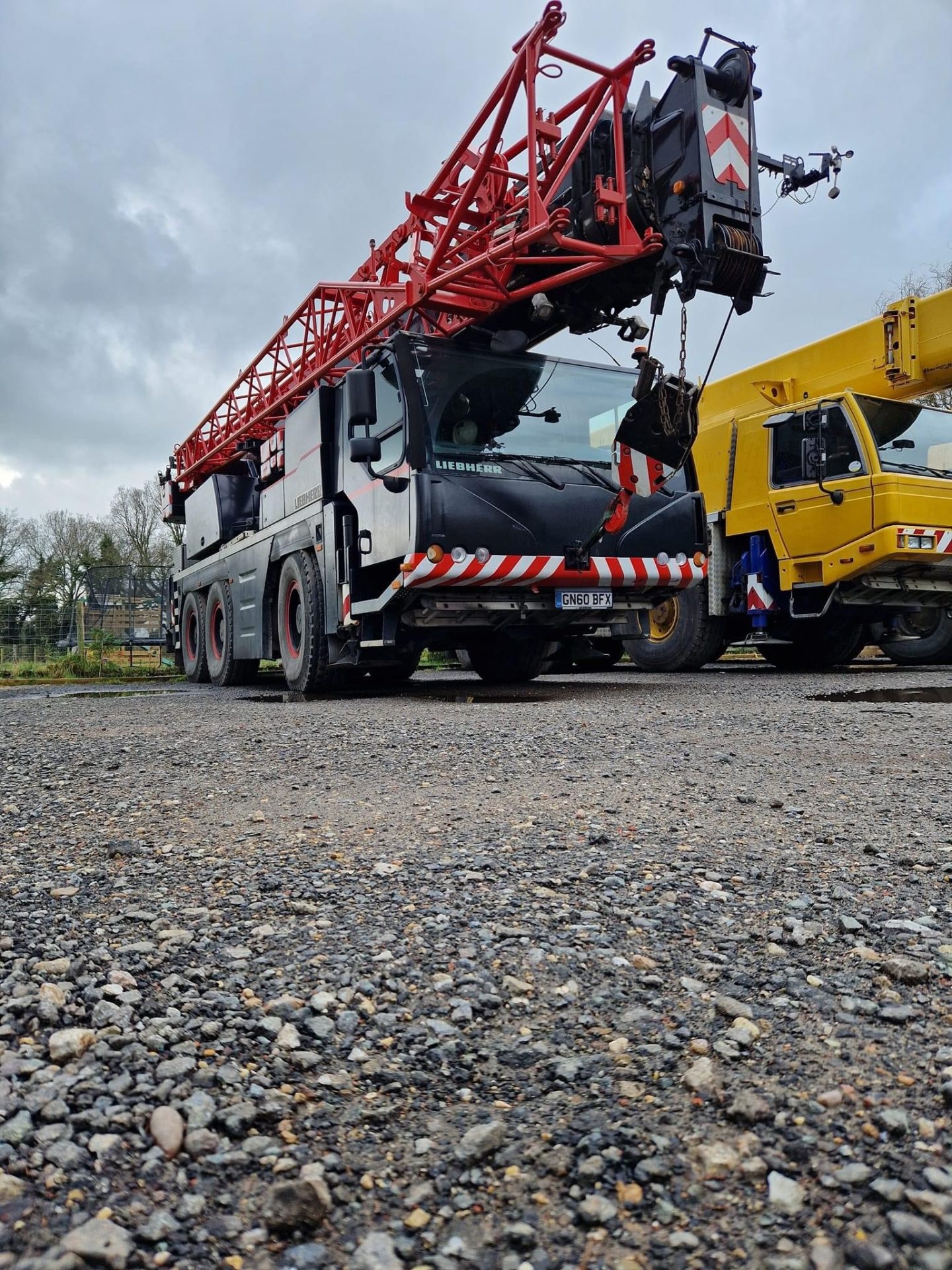 Red lattice boom crane positioned on gravel yard