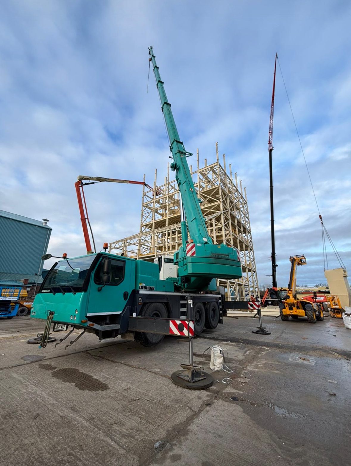 Green crane lifting structural steel on building project